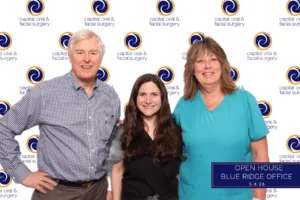 Dr. Murrell, Dr. McKay, and Cynthia smiling together in a photo booth at a Raleigh dental open house event