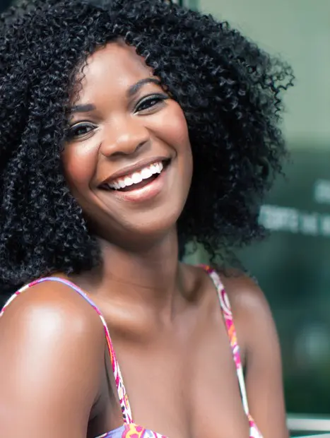 Woman smiling with healthy, beautiful teeth representing the benefits of porcelain inlays and onlays for restoring damaged teeth.